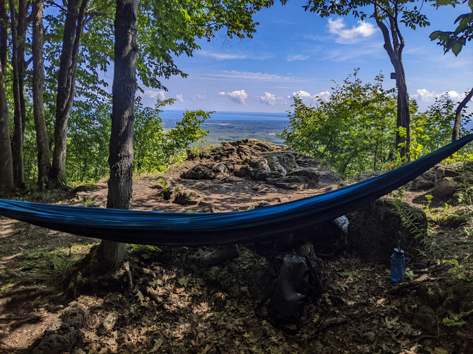 A blue hammock on top of the Niagara Escarpment looking down at Georgian bay. Hiking along the Bruce Trail near Collingwood, Ontario during the summer